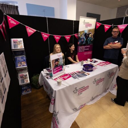 Exhibition booth with promotional materials and pink bunting displayed.