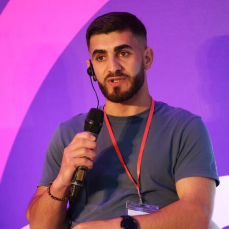 Person holding a microphone, speaking during a session.