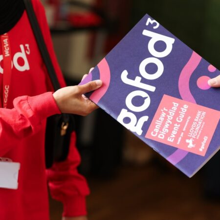Person holding a “gofod3” event brochure with a red lanyard visible.