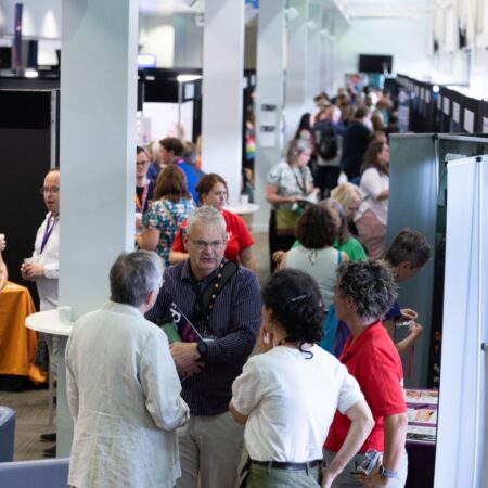 Group of attendees gathered in a busy networking area with exhibition stands.